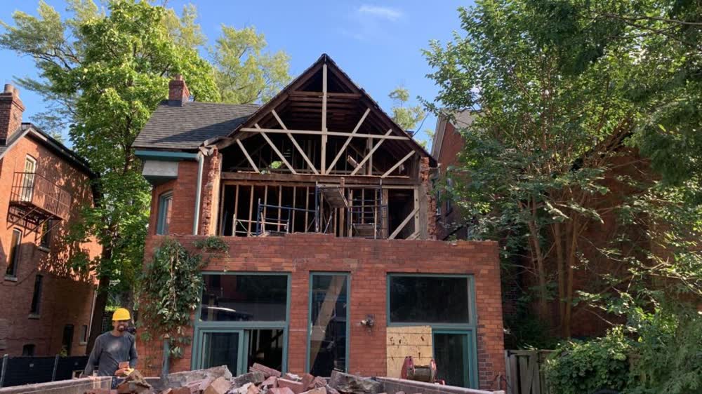Structural demolition of a brick Toronto home, roof opened and scaffolding inside