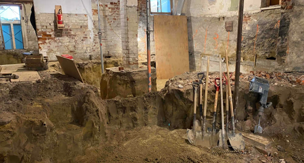 Basement underpinning in progress, pits dug in sequence against the foundation